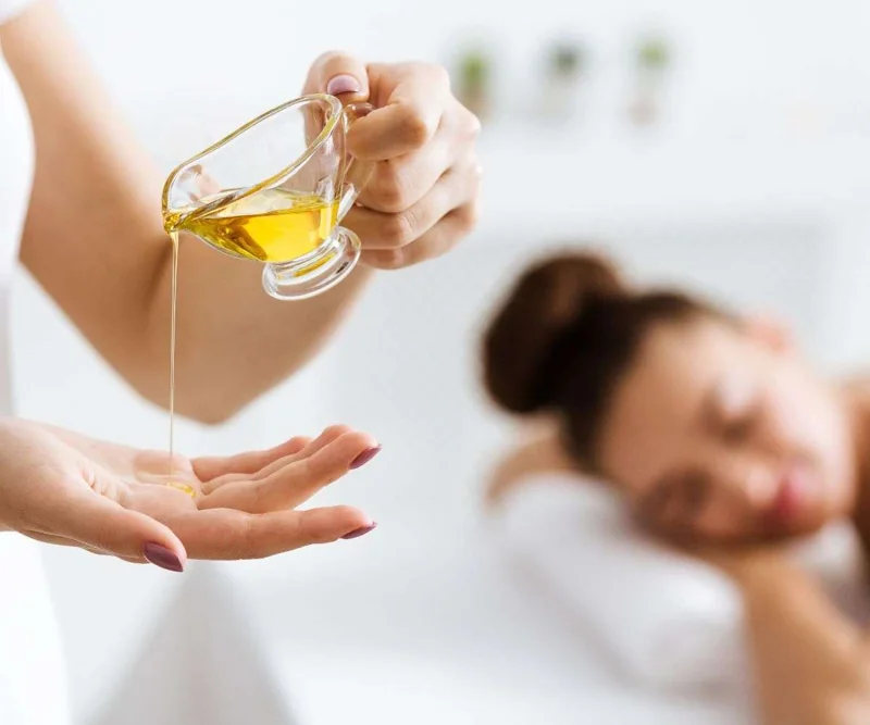 Massage oil being poured into a therapist’s hand
