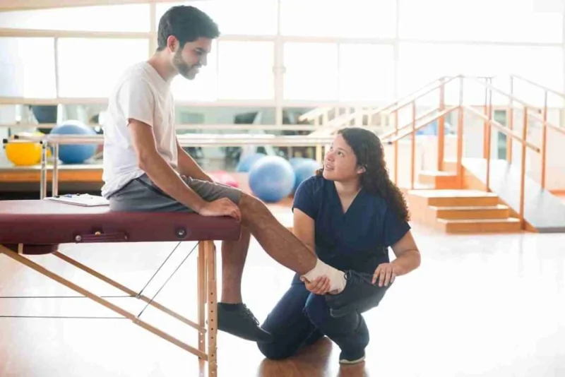 A therapist assessing a patient’s ankle